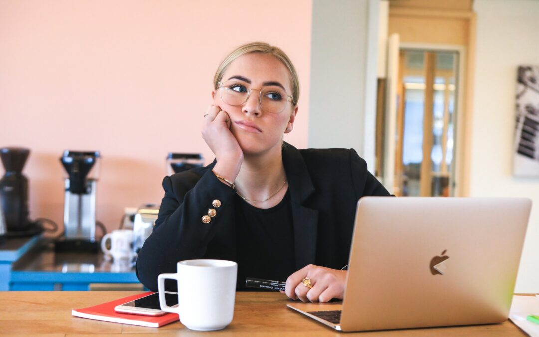 femme assise à son bureau, l'air insatisfait, représentant le besoin de changement professionnel et se demandant les signes pour changer de métier