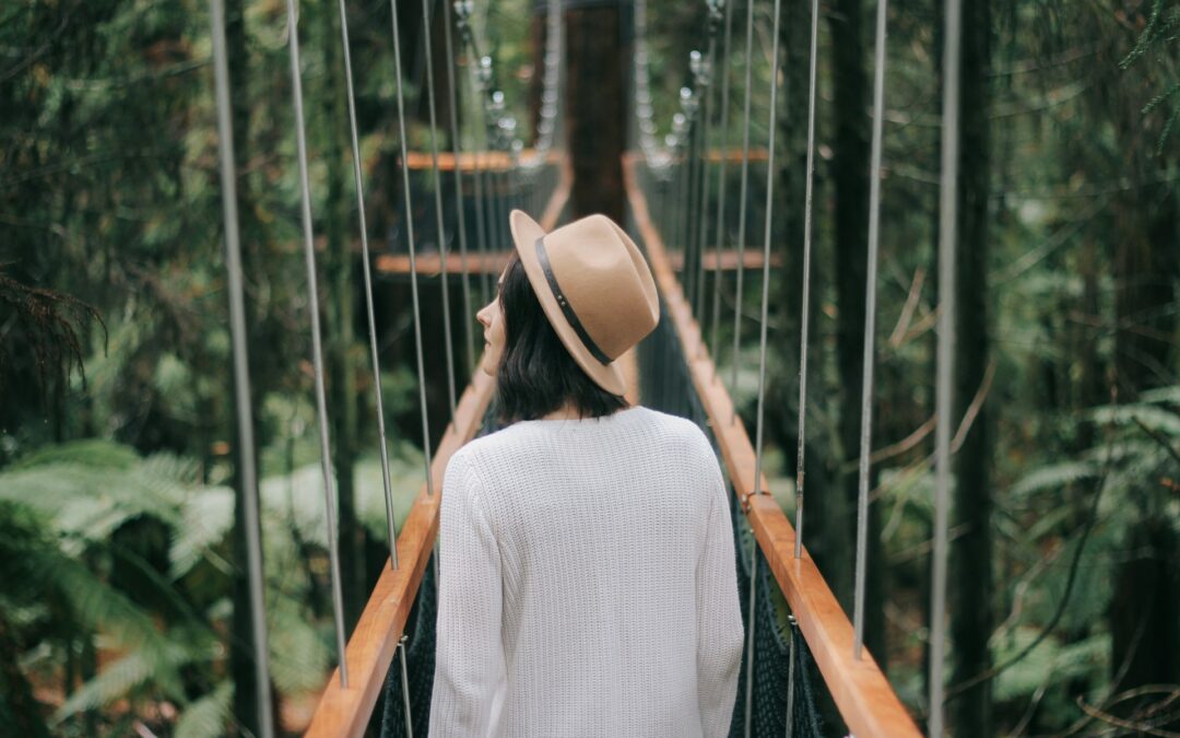 une femme sur un pont à travers une forêt dense, symbolisant à la fois la peur, l'inconnu et l'espoir.